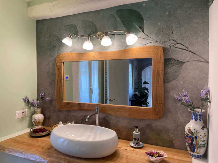 immagine con specchio in legno e lavabo rotondo
